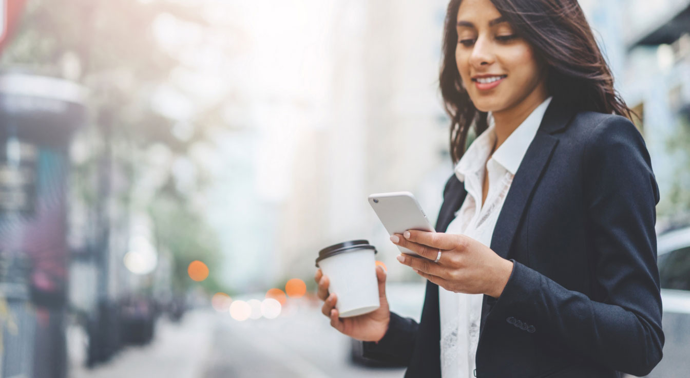Business Lady looking at her phone in one hand and holding a coffee mug on the other